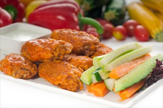 Classic buffalo chicken wings served with fresh pinzimonio and vegetables on background