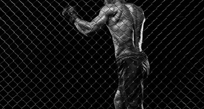 Black and white image of a man in a boxing cage. The concept of sports