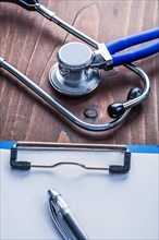 Clipboard with paper sheet and biros Stethoscope on vintage wooden board