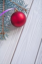 Copyspace picture mat red Christmas bauble and Christmas tree branch on white wooden panels