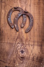 Copyspace image two old cast iron metal western horse shoeing accessory horseshoes on antique wooden background happy concept vertical version
