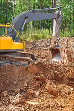 Excavator excavating clay soil on a construction site in the forest