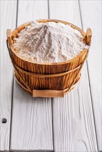 Flour in wooden buckets with handles on old white-painted wooden boards