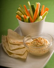 Middle eastern hummus dip on a glass bowl with homemade pita bread and raw vegetable