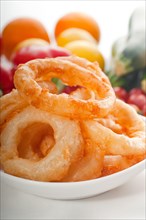 Golden deep fried onion rings served with mayonnaise dip and fresh vegetables oln background