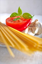 Italian spaghetti pasta tomato raw ingredients basil garlic and red chili pepper