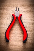 Aerial view small nippers with black red handles on wooden board