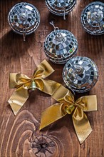 Two golden bows and Christmas disco mirror balls on an old wooden board