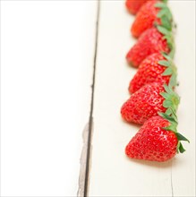 Fresh organic strawberry over white rustic wood table