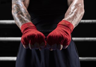 Red bandages on the hands of a kickboxer against the background of the ropes of the ring. The concept of mixed martial arts. MMA