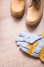 Working boots and protective gloves on wooden board construction concept