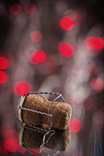 Corck of champagne on mirror surface with lights of red bokeh
