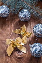 Golden Christmas bows and mirror disco balls with Christmas tree branch on an old wooden board