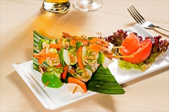 Fresh and colorfull grilled shrimps and vegetables skewers on a palm leaf