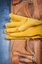 Pair of safety working gloves toolbelt on metallic background construction concept