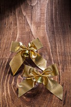 Golden bows with small bells on an old wooden board
