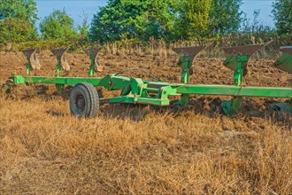 Large set of plough on field in work agricultural concept