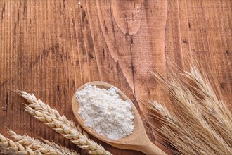 Copyspace image white natural flour in spoon and ears of wheat and rye on vintage wooden board