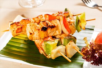 Fresh chicken and vegetables skewers on a palm leaf thai style