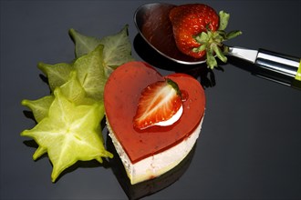 Heart shaped strawberry cake with carambola or star fruit decoration over black background