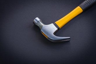 Close-up horizontal view Claw hammer with yellow and rubberised handle on black background