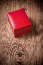 Gift box with red leather cover on old brown wooden board