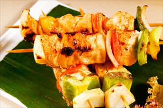 Fresh chicken and vegetables skewers on a palm leaf thai style