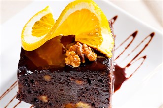 Fresh baked delicious chocolate and walnuts cake with slice of orance on top