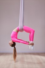 Image of a beautiful woman posing in a bright studio near the hammocks. The concept of airstretching. Fitness and sports