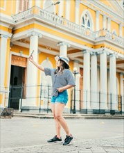 Beautiful tourist in hat taking selfie in the cathedral of Granada. Young travel woman taking a selfie in a public square
