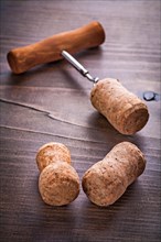 Champagne corks and corkscrew on vintage wooden board alcohol concept