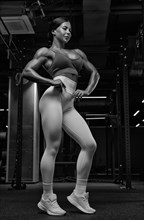 Black and white image of a sexy fitness woman. A beautiful sportswoman is training in the gym. Mixed media