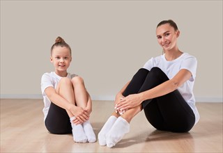 Beautiful female teacher poses with a little girl in a gymnastics class. The concept of education