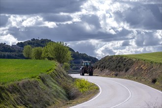 Tractor driving on a country road between crop fields in the province of Valladolid in Spain