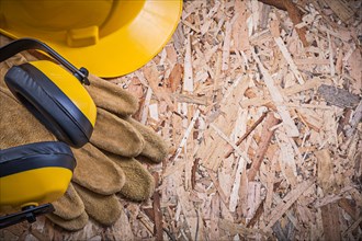 Protective leather gloves hard hat earmuffs on OSB