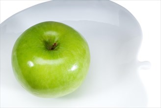Green apple on a apple shaped dish isolated over white