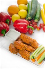 Classic buffalo chicken wings served with fresh pinzimonio and vegetables on background