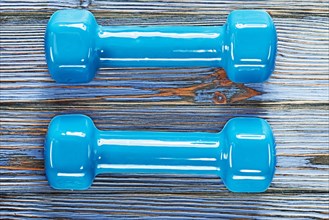 Blue fitness dumbbells on vintage wooden board