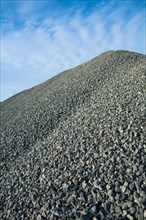 Close up view on big pile of grey gravel on background of blue sky