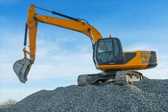 Excavator on big pile of gravel