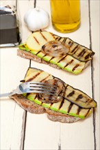 Grilled vegetables on rustic bread over wood table
