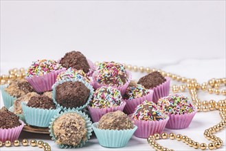 Dark rum balls with various sprinkles in pink and turquoise paper moulds