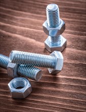 Group of stainless steel threaded bolts and nuts on vintage wooden board construction concept