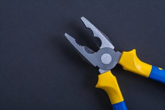 Open pliers on a black background