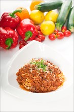Italian classic spaghetti with bolognese sauce and fresh vegetables on background