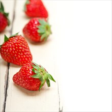 Fresh organic strawberry over white rustic wood table