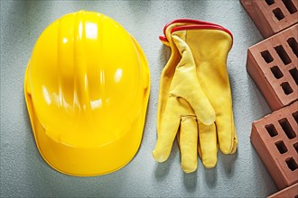 Red building bricks protective hard hat leather safety gloves on concrete background construction concept