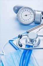Clipboard with white blank paper masks stethoscope blood pressure monitor on blue background medical concept