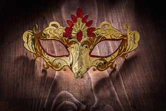 Gold-coloured carnival mask on an old wooden board