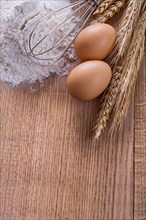 Organised copyspace heaf of four eggs corolla wheat ears on wooden board food and drink concept